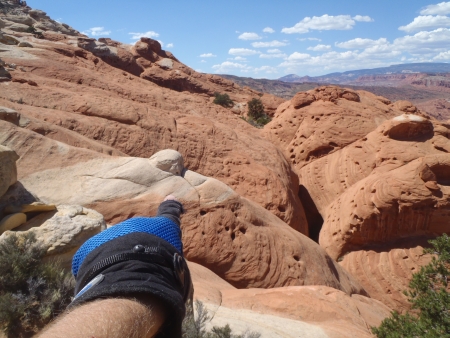 View down over the sea of orange slick rock around the top of Wife 5 with the round white knob in the center.